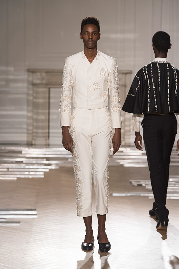 runway image of model wearing off-white suit with bead design going down sleeves and legs