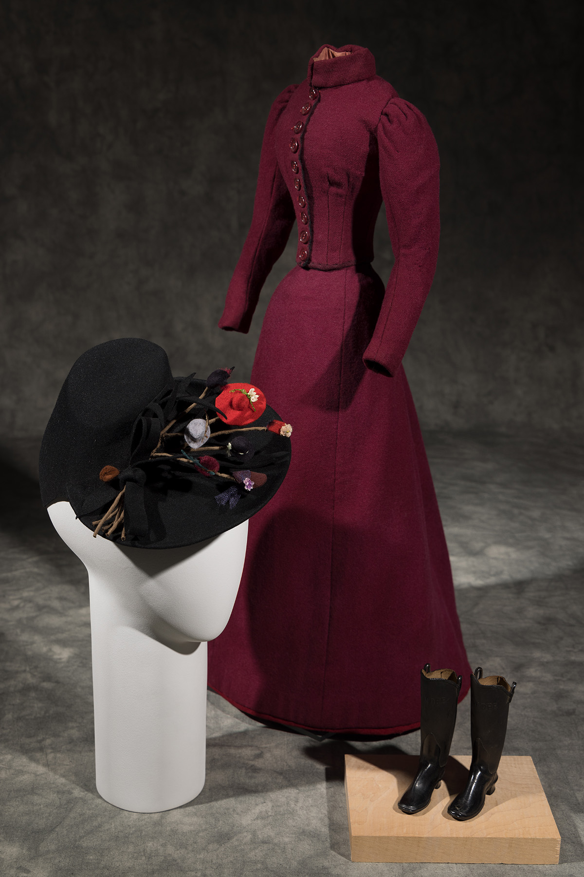 black hat adorned with tiny hats; tiny brown boots; and marroon dress