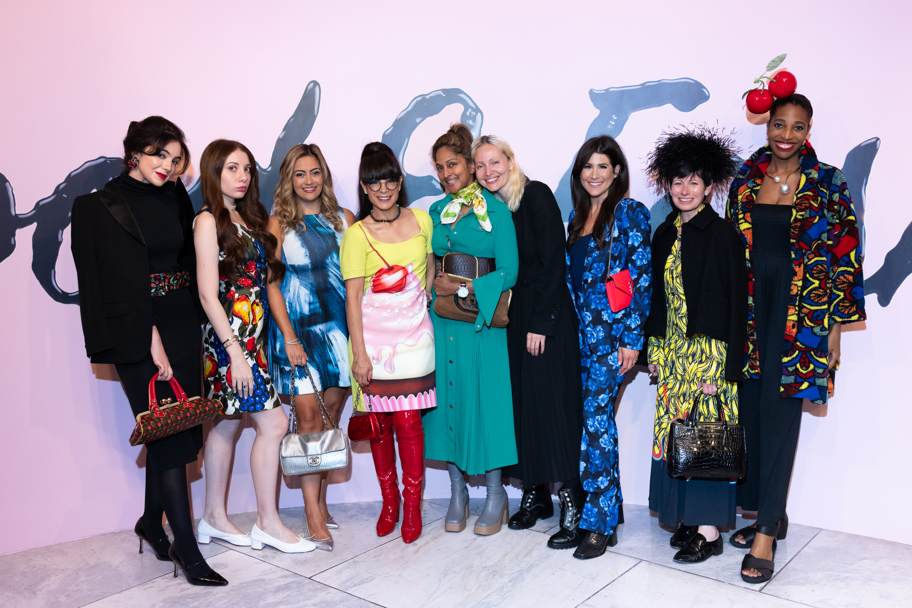 couture council young patrons posing in front of the food and fashion exhibition wall graphic