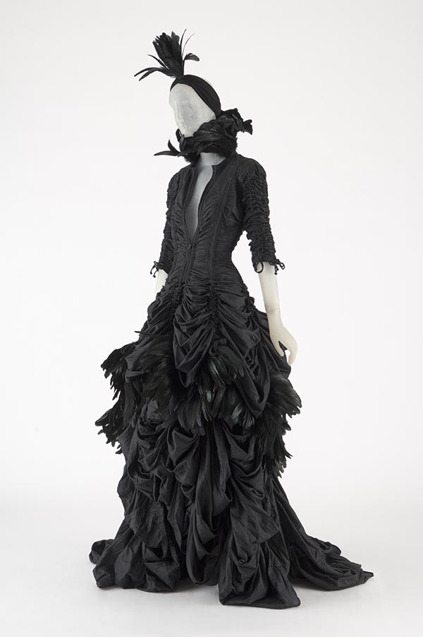 black parachute cloth and feather jacket with a black skirt and feathered turban
