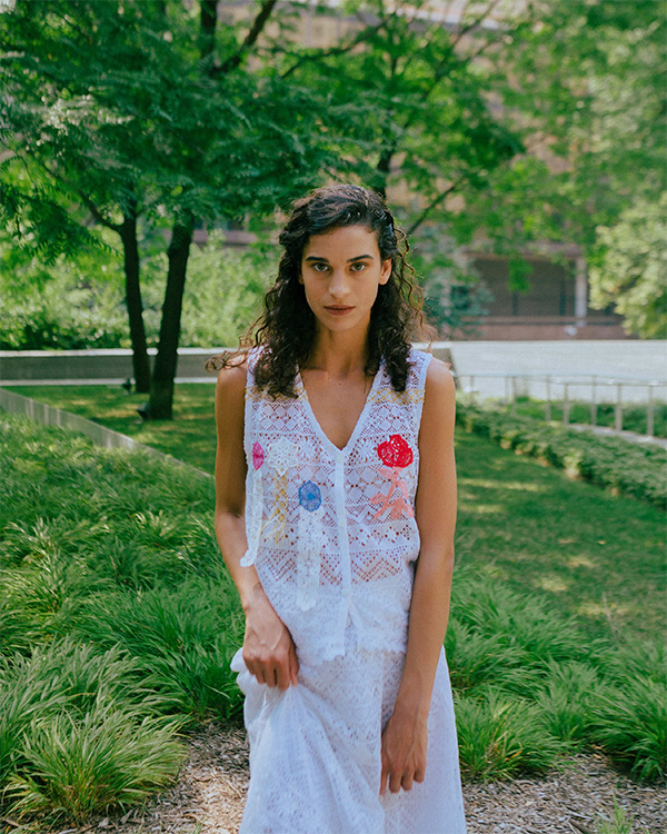 a woman wearing a white woven ensemble in a garden