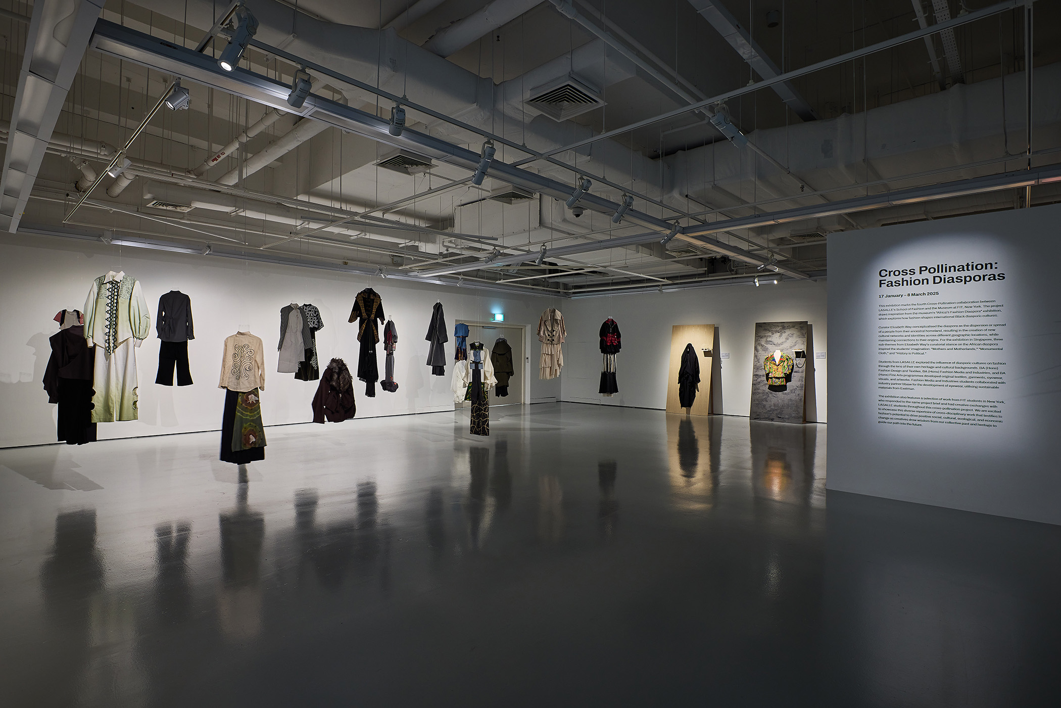 ensembles hanging in a gallery, with two ensembles intalled on large wooden planks leaning on a wall