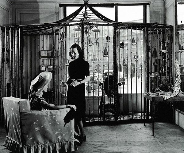 two women in front of a large birdcage in a perfume boutique