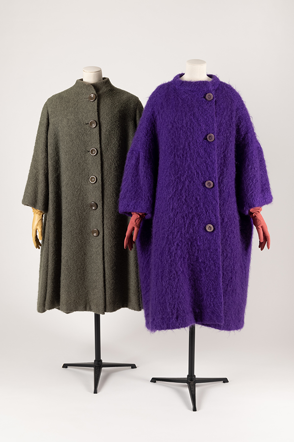 two simlar coats on dress forms. One grey, one purple
