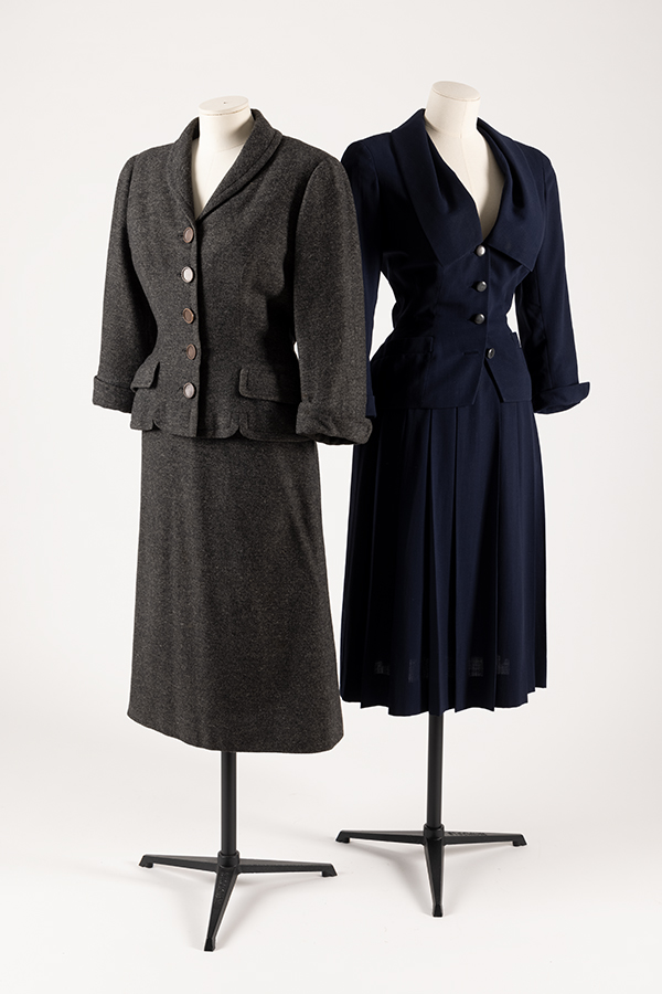 two wool women's suits on mannequins. One grey, one black 