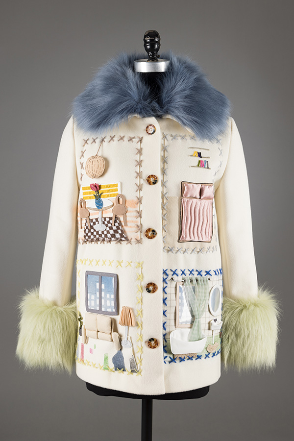 white coat decorated with embroidered or appliquéd scenes depicting miniature domestic interiors and objectswith blue faux fur collar and green faux fur cuffs