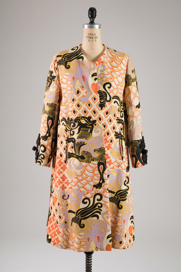 white linen coat printed with winged animal design in black, gold, mauve interspersed with red, gold, black floral and diamon design