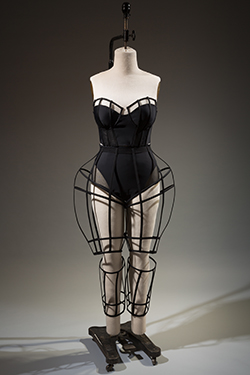 black bustier with padded bra cups and cage overlay; full bried panties with sheer mesh insets at thighs and articulated cage pants