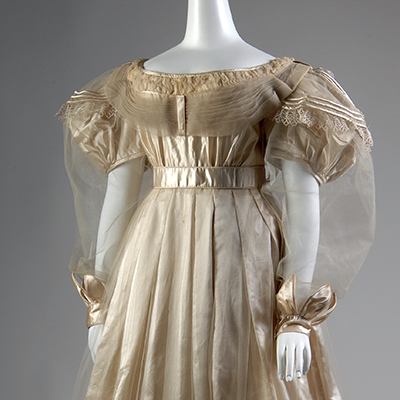 Cream silk satin ballgown with attached tulle overdress; empire waist, and short puffed sleeves