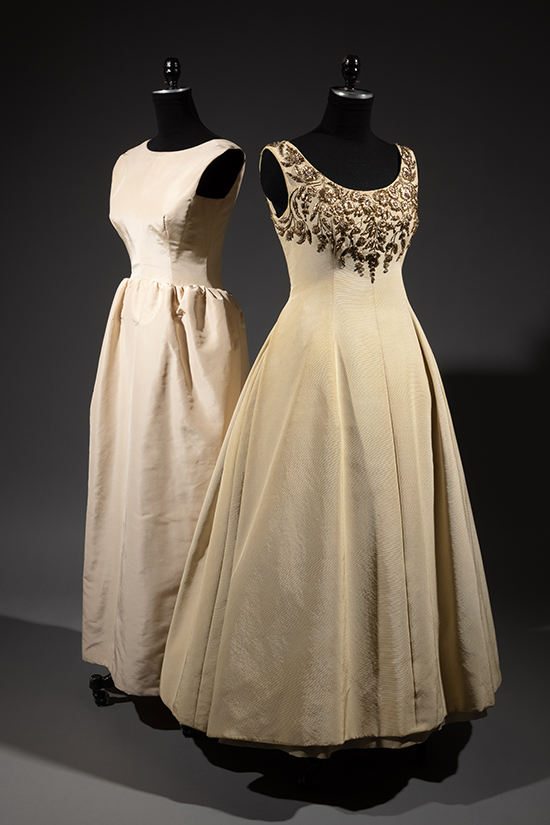 two cream-colored floor-length evening gowns on mannequins