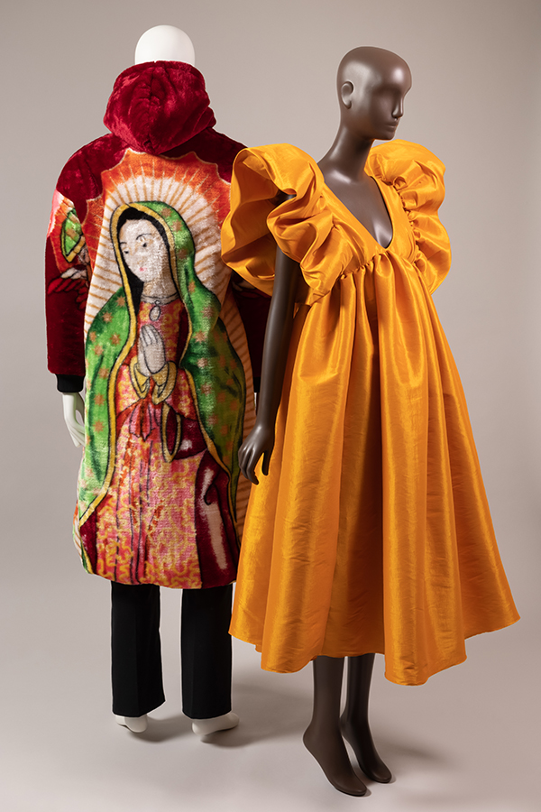 back view of hooded coat with Virgin de Guadalupe paired with vibrant orange dress with giant ruffle sleeves