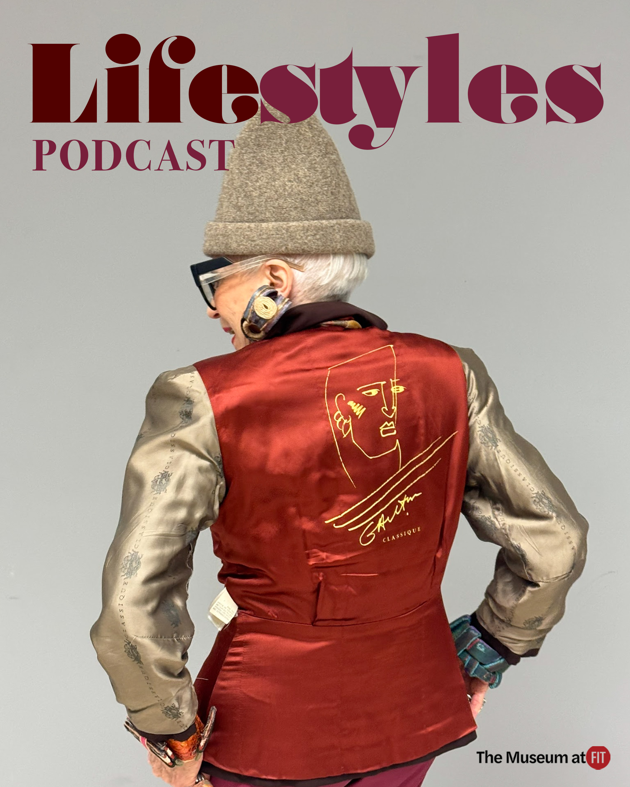Stylish older woman in a beige hat and metallic sleeves, posing with her back to the camera highlighting a red jacket's artistic back design.