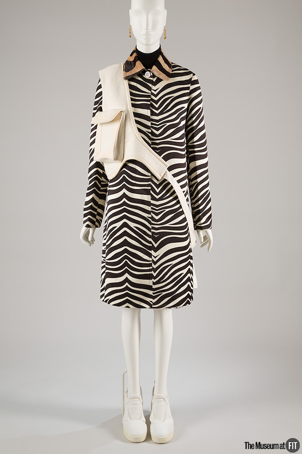 zebra print coat with black turtleneck and skirt, off white cross body bag, gold ball earrings, and white leather sneakers