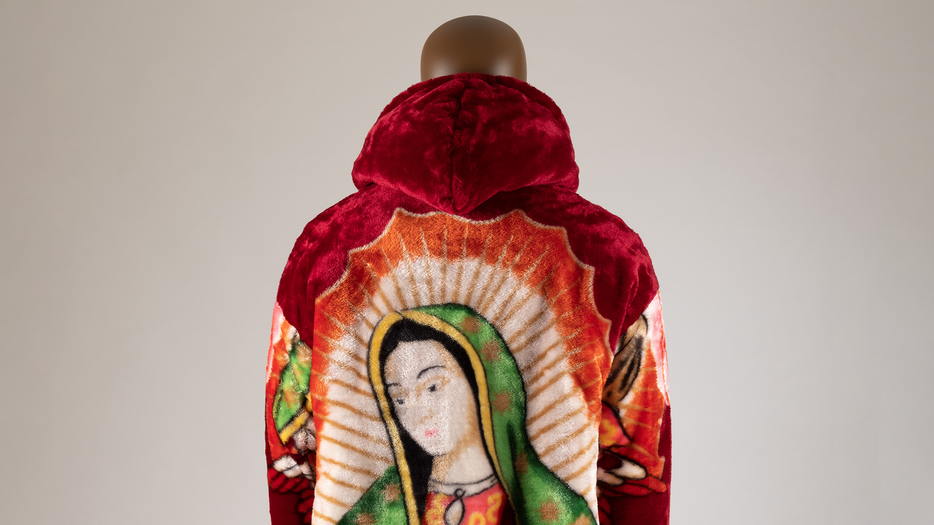 Parte trasera de un abrigo de tela voluminosa con la imagen de la Vírgen de Guadalupe.