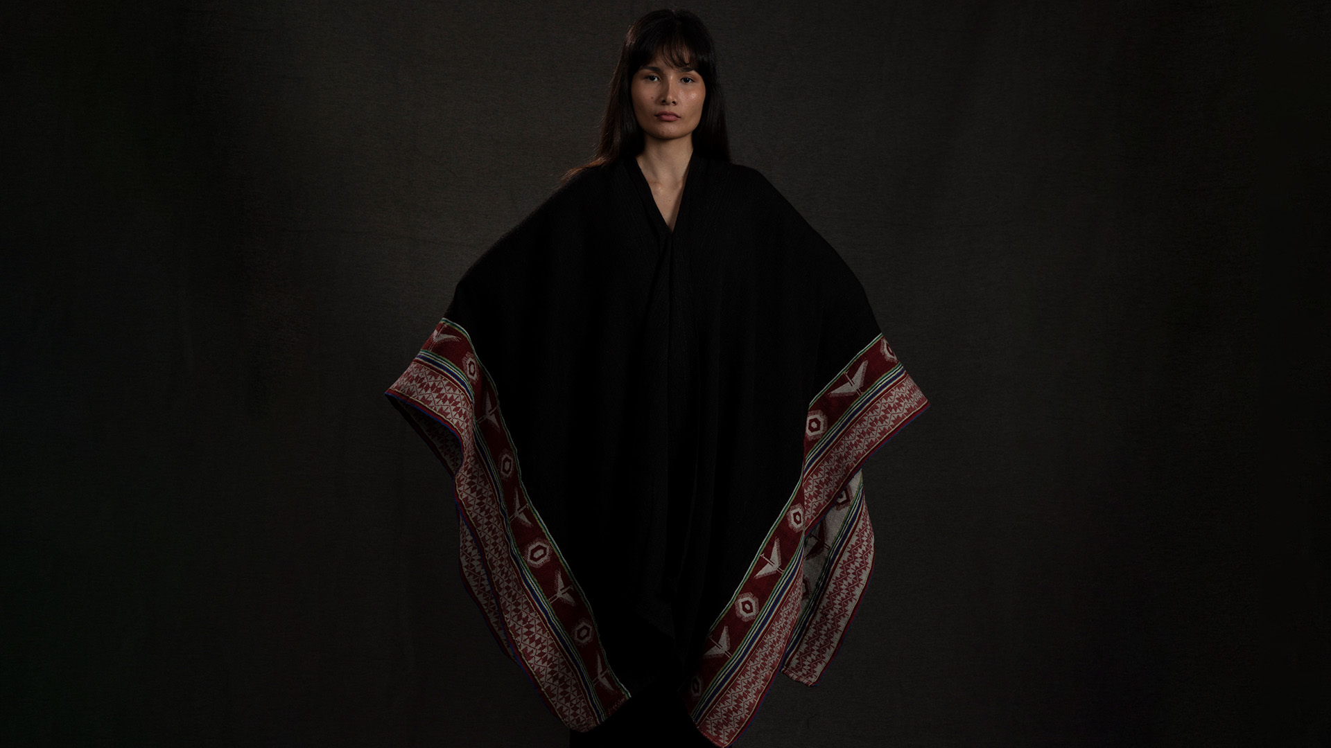 Modelo vestida con una capa con motivos indígenas de el ruedo.