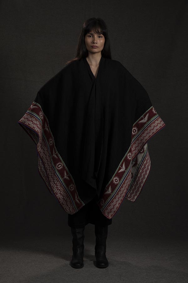 model wearing a cape with indigenous patterns along the trim