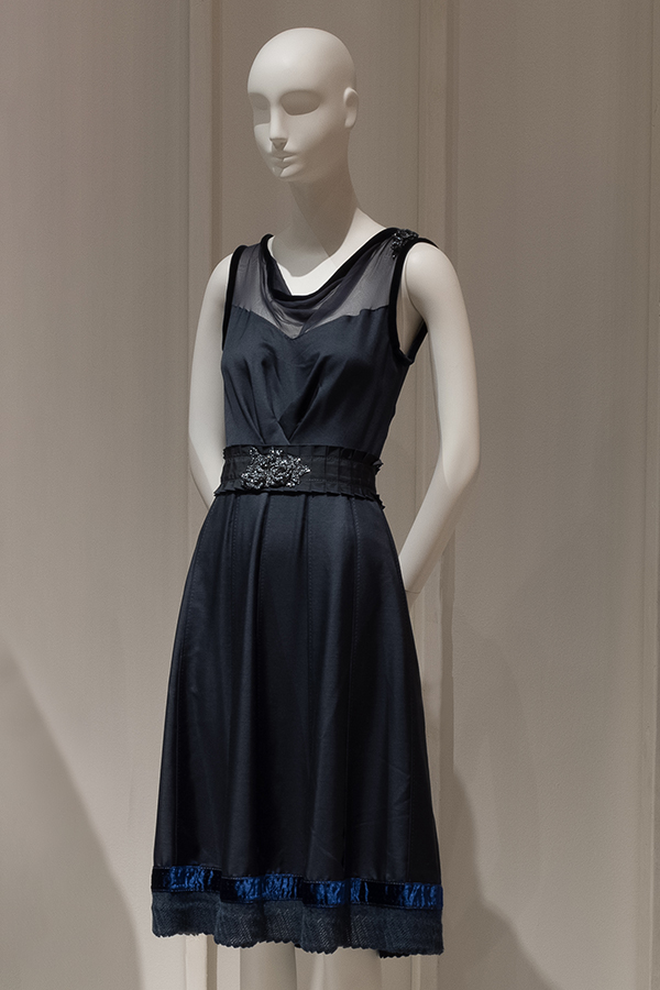 Dark blue sleeveless cocktail dress with velvet trimmed chiffon neckline and armholes, softly pleated knee-length skirt, knitted hemline and floral beading at box pleated waistband