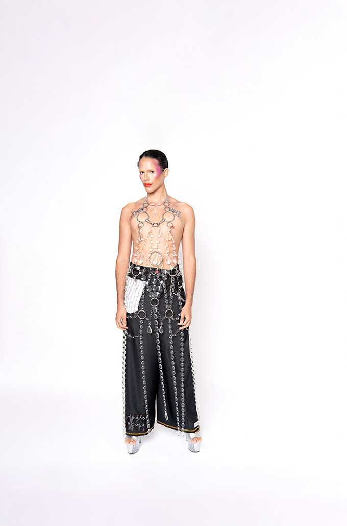 androgynous model wearing silver chain tunic over black wide leg pants and chrome platform heels