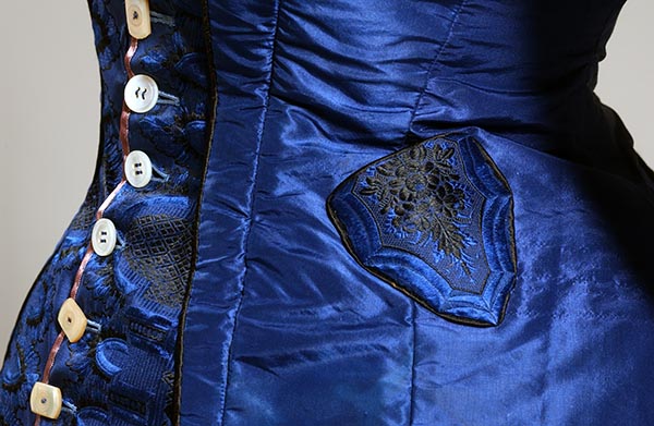 detail image of small watch pocket on left hip of royal blue bodice with black embroidery