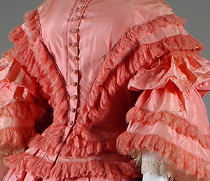 pink dress with tiers of fringe-trimmed taffeta, corset bodice and belled sleeves
