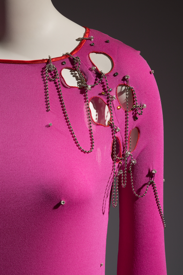 top detail of hot pink body fitting ensemble with punk holes and chain decoration