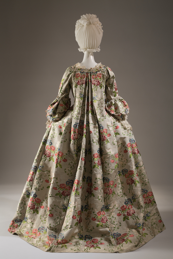Robe la franaise of brocaded silk with flower sprays in shades of red, peach, pink, blue, and green and leaves meander pattern on cannele ground