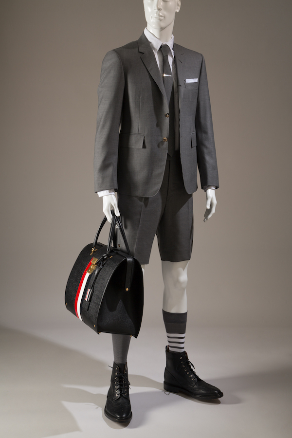 man's ensemble; grey wool short suit, jacket, shorts, tie, white cotton shirt, pocket square, silver tie bar, black leather wingtip boots and grey socks