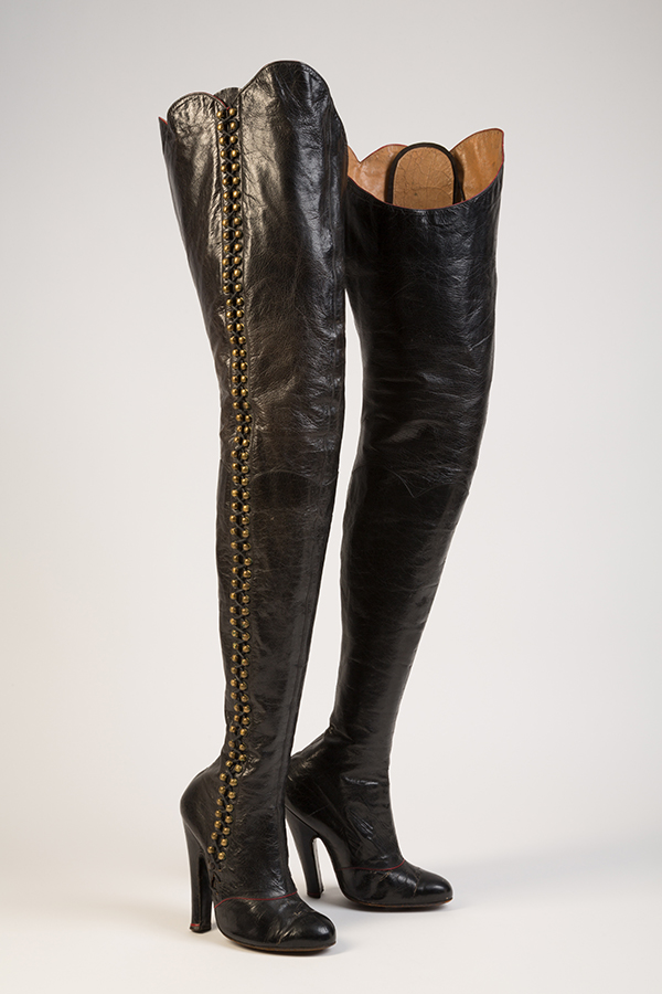 black thigh-high lace up boots with 118 brass hooks at outside leg opening and black laces