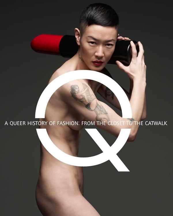 a person, nude with tattoos on their arm, holding a giant lipstick tube with the letter "Q" superimposed on white 