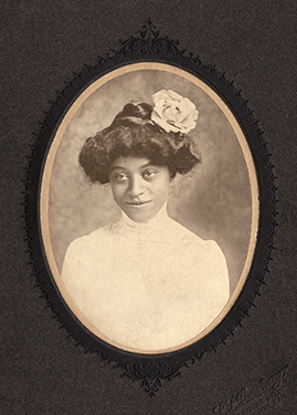 Vintage photograph of a black woman in a white dress with a white rose in her hair