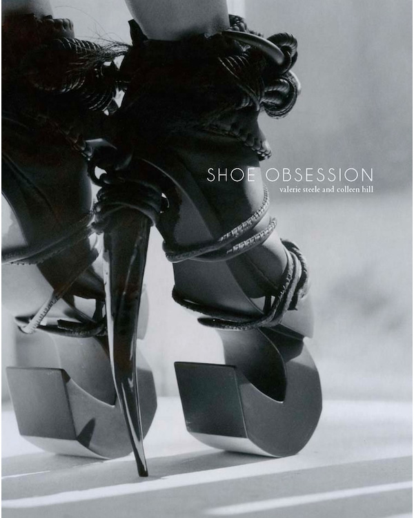 black and white image of a pair of heels with geometric round platforms and pointed sharp heels and ropes