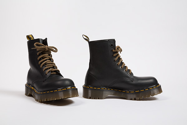 Heavy black leather work boots with thick brown striped laces, yellow topstitching and tan rubber lug sole, round bulldog toe, back logo ribbon loop