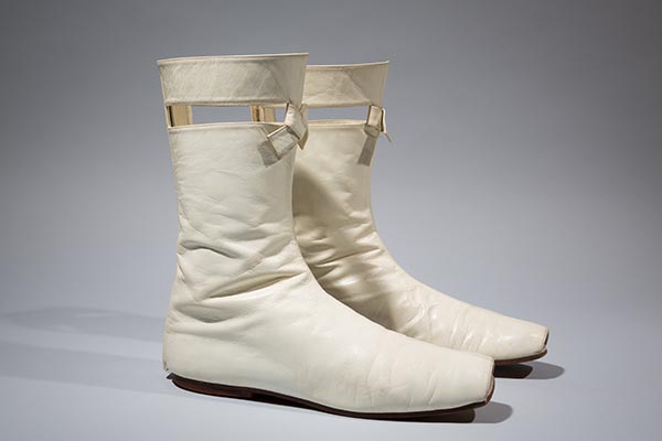 Futuristic go-go boots in off white kid leather, with cut-out slit and self knot at top; flat heel and open toe; CB zipper and velcro closure