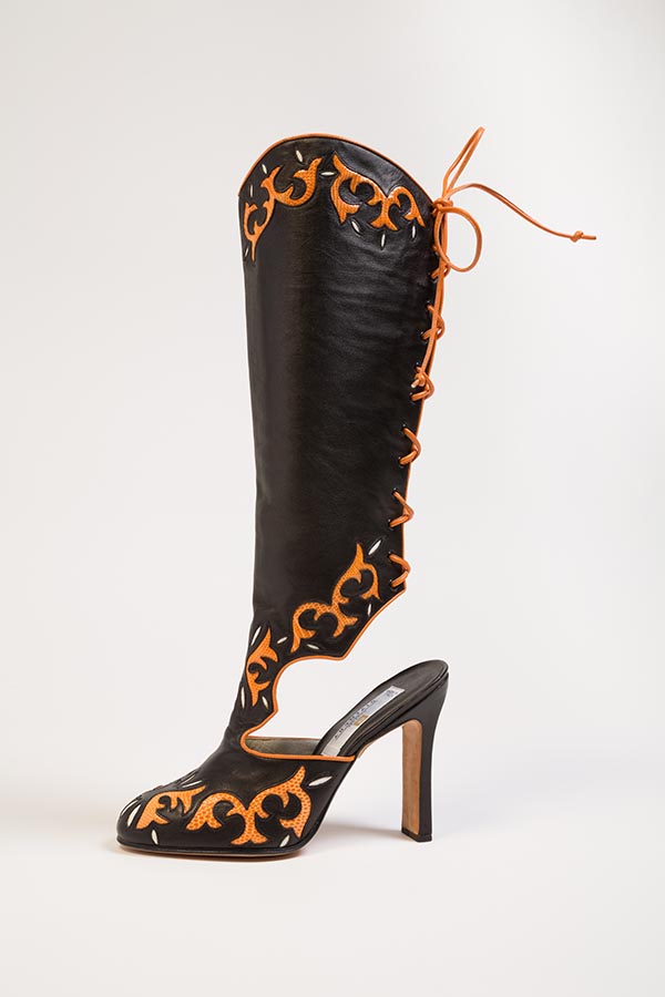 High, back laced western style evening boot in black leather with orange lizard inserts, orange leather piping and lacing; scallop cut open counter, sculpted rectangular stiletto heel, rounded point toe; right boot