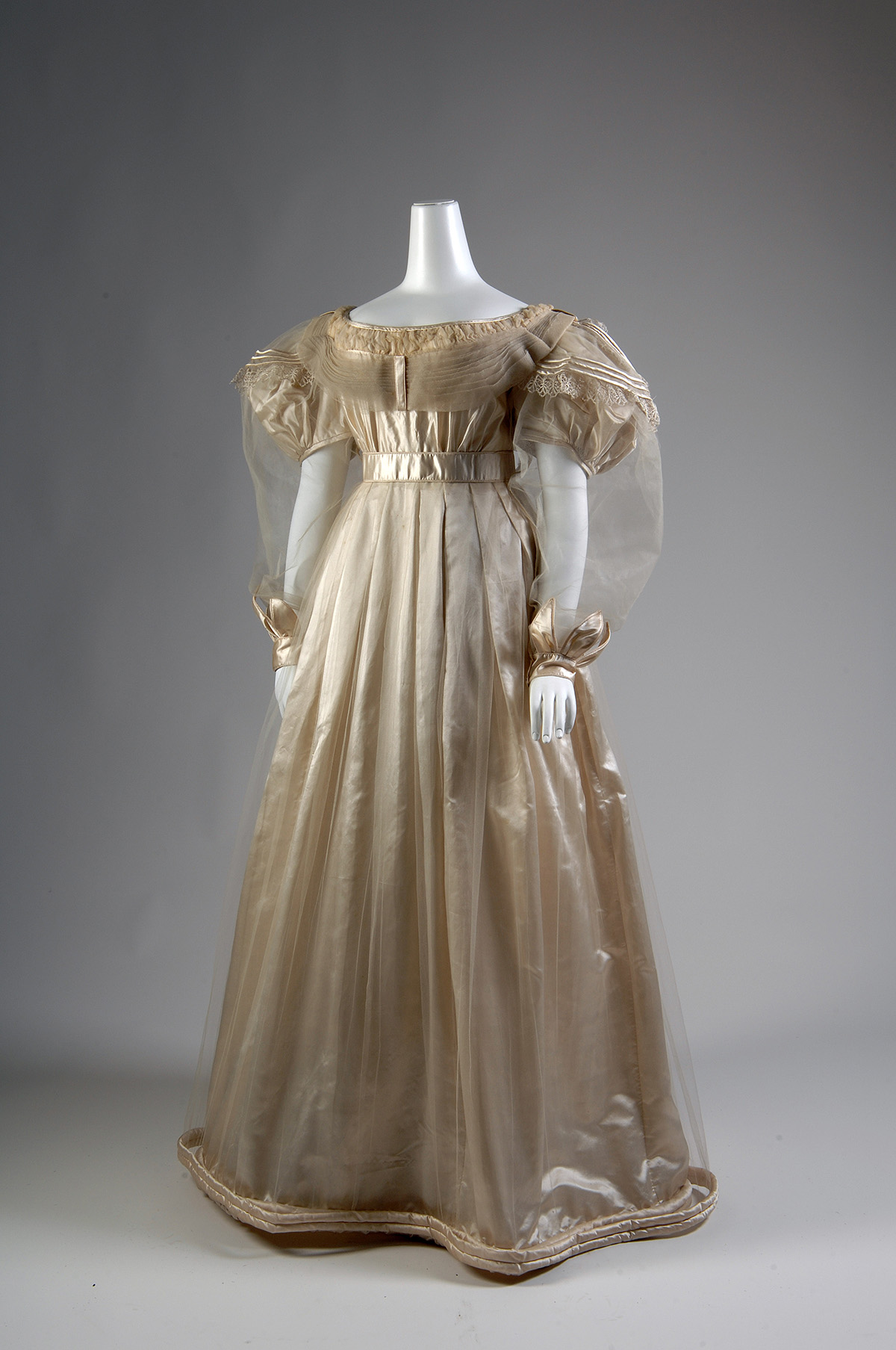 The bodice of ballgown made from cream silk satin. It has short, puffed sleeves with a long oversleeve crafted from sheer silk tulle.