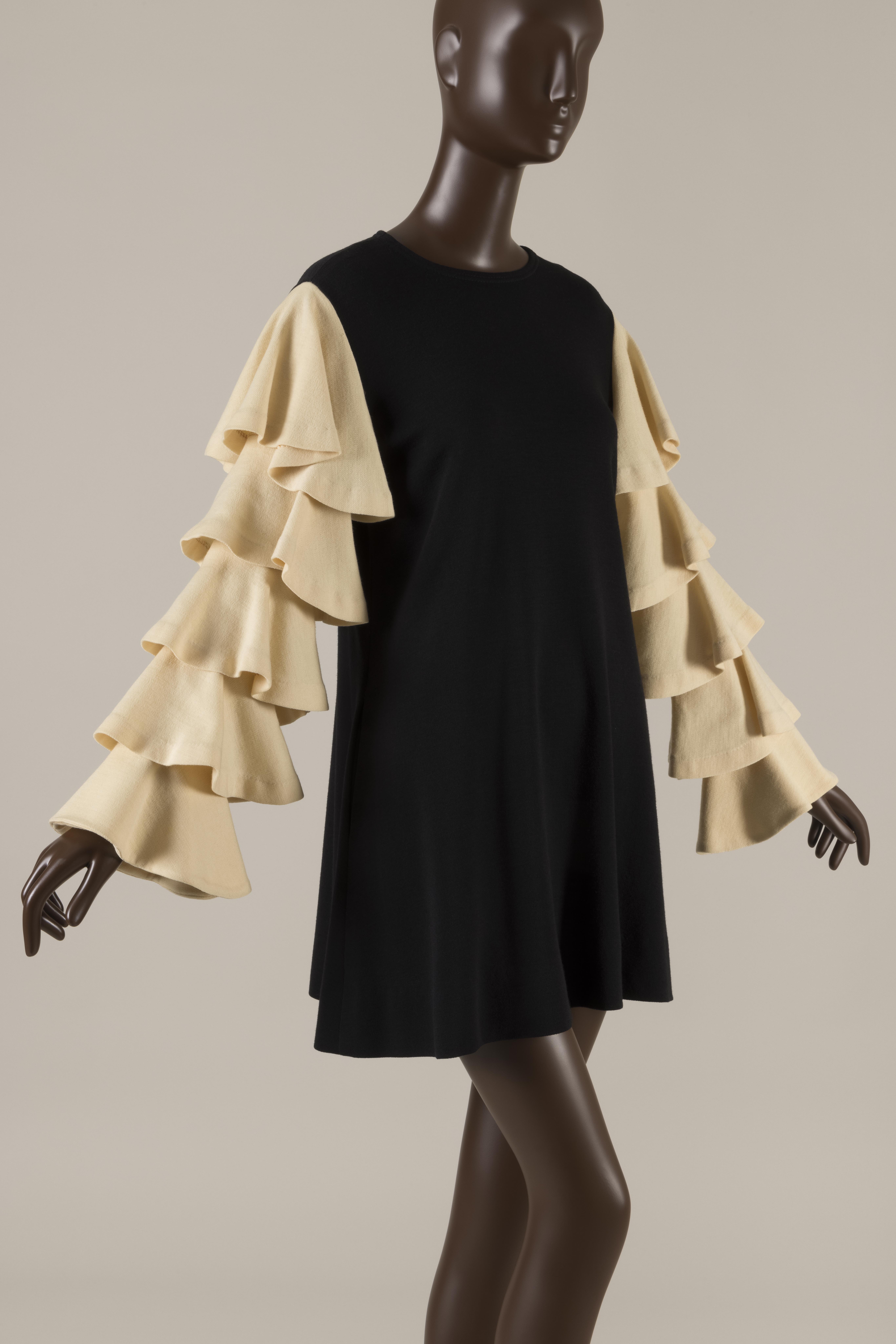 black wool dress with a high neckline and cream colored tiered ruffle sleeves
