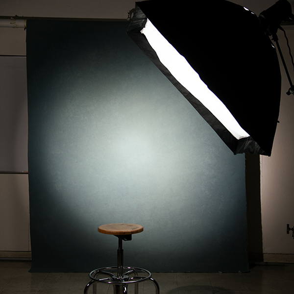 blue-gray photography backdrop with stool and spotlight