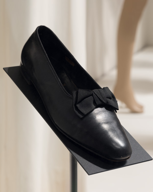 one black opera pump with a black bow at the vamp, or front of the shoe