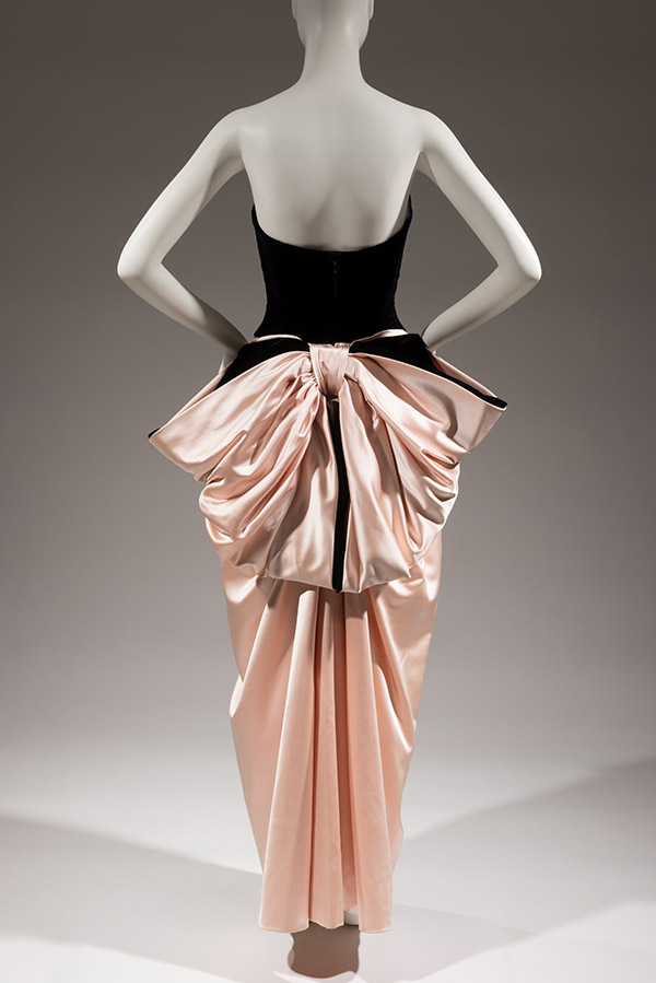 back view of a dress with a black velvet corset bodice and a pink satin stylized peg skirt with bustle bow