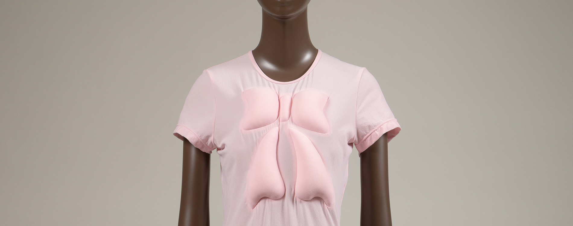 baby pink short sleeved dress with two large bows on the bust and hip