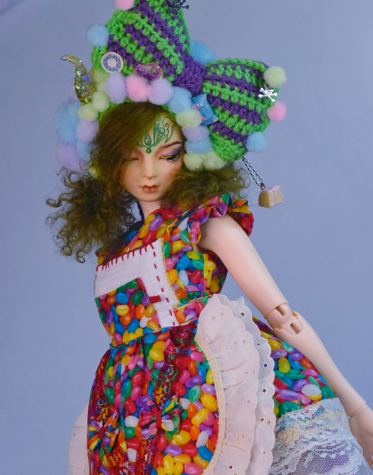 doll wearing a jellybean short sleeved dress and a large, green and blue crochet bow in her hair